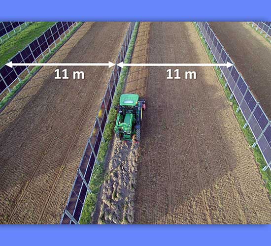 Farm vehicle passing between solar panels